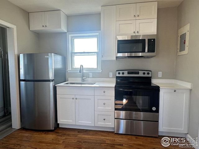 kitchen with a sink, white cabinets, appliances with stainless steel finishes, and dark wood finished floors