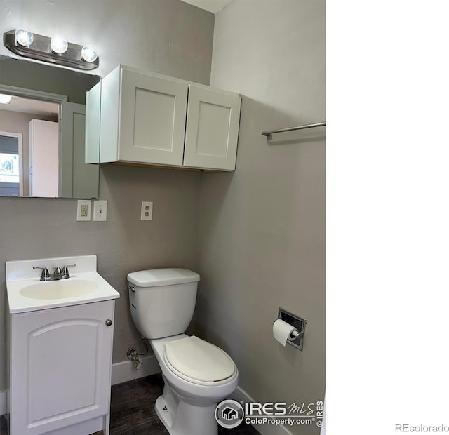 bathroom featuring toilet, wood finished floors, vanity, and baseboards