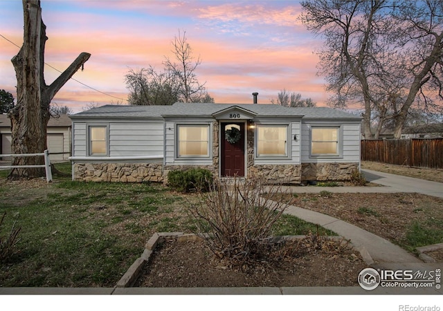 800 W 10th St, Loveland, CO 80537 - view of front of property featuring fence, stone siding, and a lawn