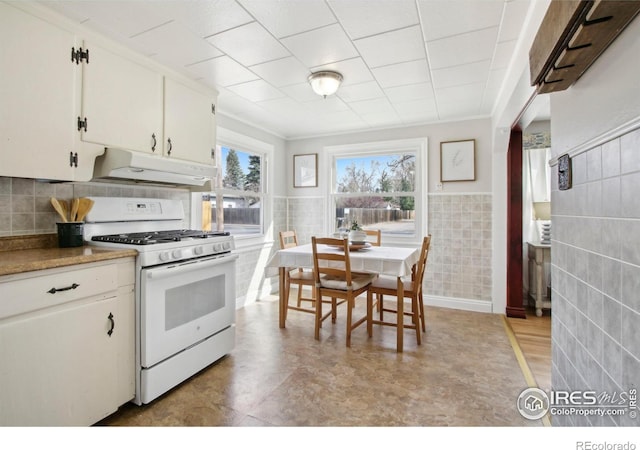 800 W 10th St, Loveland, CO 80537 - kitchen with tile walls, under cabinet range hood, white gas stove, white cabinetry, and wainscoting