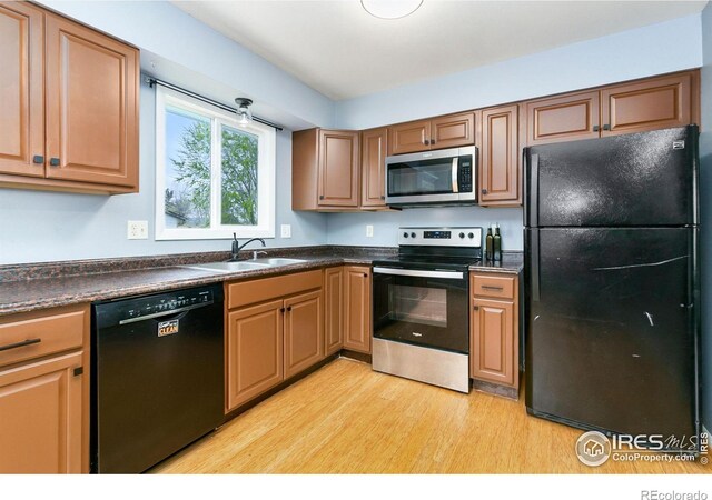 8205 Hallett Ct, Fort Collins, CO 80528 - kitchen with light wood finished floors, a sink, black appliances, and dark countertops