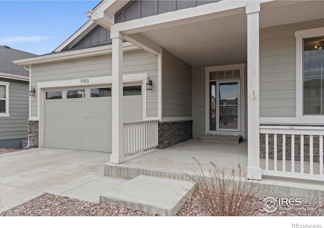 1103 Hornet Dr, Fort Collins, CO 80526 - doorway to property featuring concrete driveway, board and batten siding, stone siding, and an attached garage