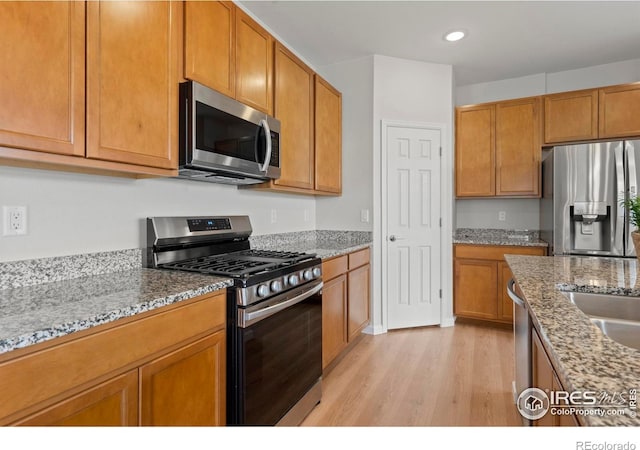 1103 Hornet Dr, Fort Collins, CO 80526 - kitchen featuring light stone counters, recessed lighting, light wood-style floors, brown cabinets, and stainless steel appliances