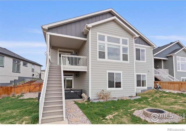 1103 Hornet Dr, Fort Collins, CO 80526 - rear view of property with board and batten siding, stairs, a hot tub, a yard, and fence