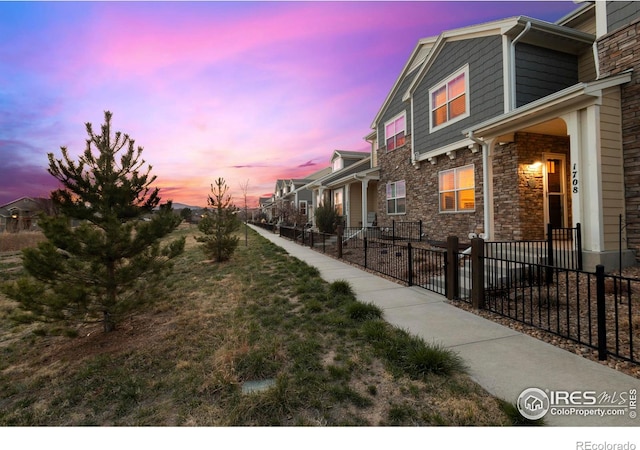 1708 W 50th St, Loveland, CO 80538 - property exterior at dusk with a residential view, stone siding, and a fenced front yard