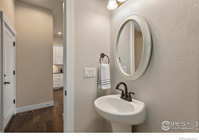 1708 W 50th St, Loveland, CO 80538 - bathroom featuring tasteful backsplash, wood finished floors, a textured wall, and a sink