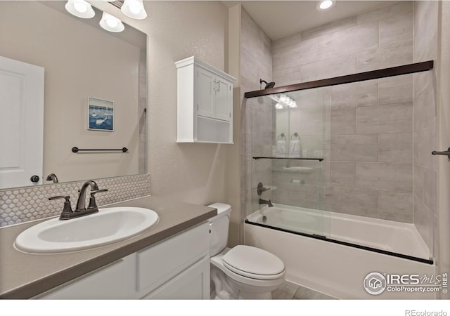 1708 W 50th St, Loveland, CO 80538 - full bathroom featuring toilet, a textured wall, vanity, shower / bath combination with glass door, and decorative backsplash