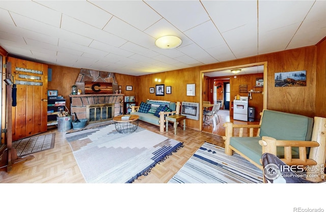 living area with wood walls, heating unit, and a stone fireplace