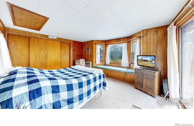 bedroom with light carpet and wood walls