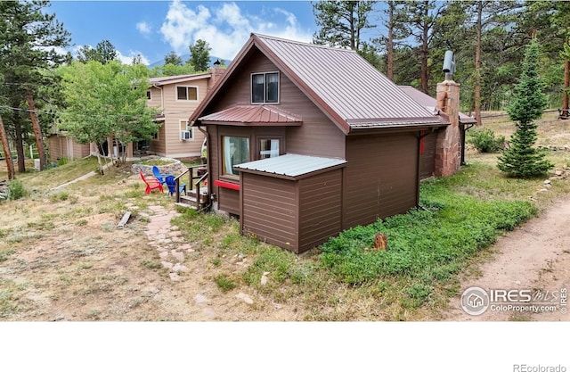 rear view of house with a chimney and metal roof