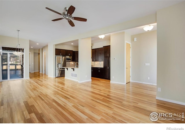 3620 Paonia St, Boulder, CO 80301 - unfurnished living room featuring ceiling fan with notable chandelier, light wood-style flooring, visible vents, a sink, and baseboards