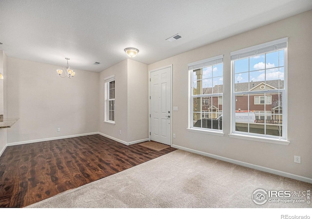 foyer featuring visible vents, baseboards, a notable chandelier, and a textured ceiling