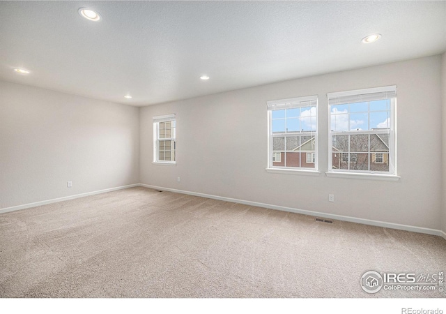 unfurnished room featuring a wealth of natural light, recessed lighting, and carpet