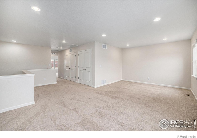 carpeted empty room with recessed lighting, visible vents, and baseboards
