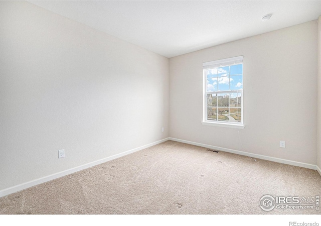carpeted spare room featuring visible vents and baseboards