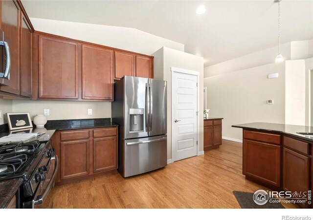 kitchen with stainless steel appliances, lofted ceiling, light wood-style flooring, and dark countertops