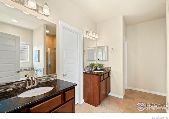 bathroom featuring two vanities, baseboards, a stall shower, tile patterned floors, and a sink