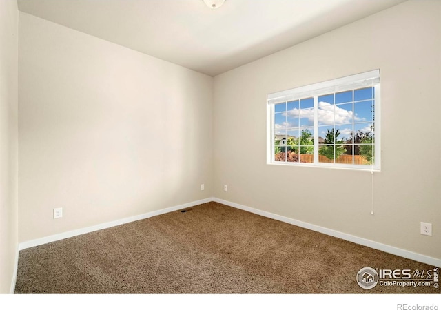 carpeted empty room featuring baseboards