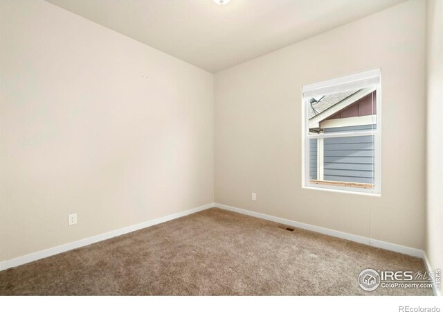 spare room with carpet flooring, baseboards, and visible vents