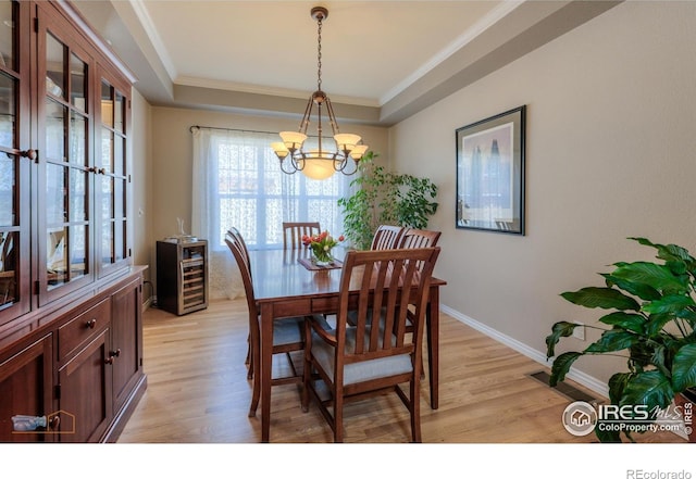 4921 Fountain St, Boulder, CO 80304 - dining room with a chandelier, light wood-style flooring, a tray ceiling, ornamental molding, and baseboards
