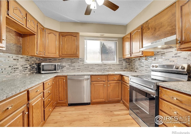 3735 W 8th St, Greeley, CO 80634 - kitchen featuring under cabinet range hood, brown cabinetry, ceiling fan, stainless steel appliances, and light wood finished floors