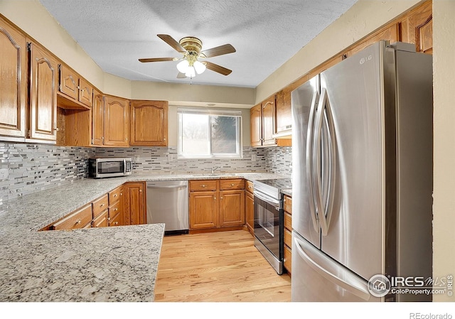 3735 W 8th St, Greeley, CO 80634 - kitchen featuring light wood-type flooring, a textured ceiling, brown cabinets, ceiling fan, and stainless steel appliances