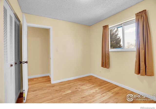 3735 W 8th St, Greeley, CO 80634 - unfurnished bedroom with baseboards, light wood-style floors, and a textured ceiling