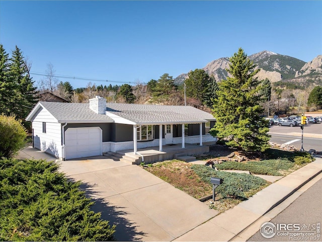 2610 Heidelberg Dr, Boulder, CO 80305 - ranch-style home with concrete driveway, a mountain view, a chimney, a garage, and covered porch