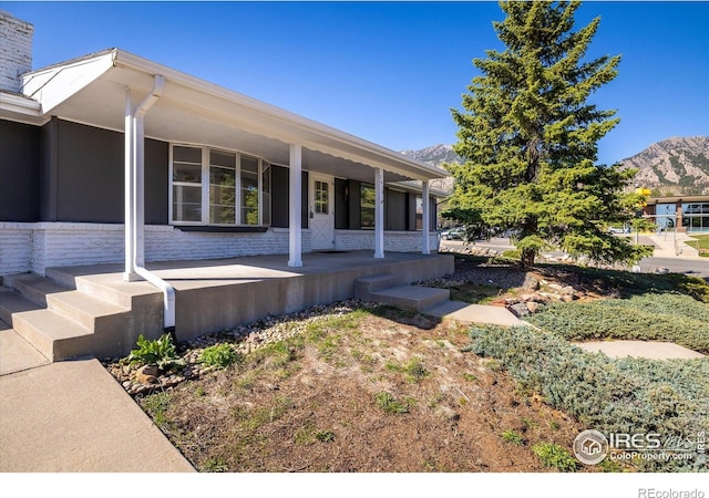 2610 Heidelberg Dr, Boulder, CO 80305 - view of home's exterior with a mountain view, stone siding, covered porch, and a chimney