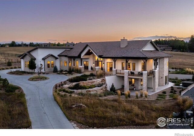view of front of house featuring a chimney, curved driveway, stone siding, and stucco siding