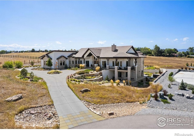 modern inspired farmhouse with stucco siding, a chimney, and curved driveway