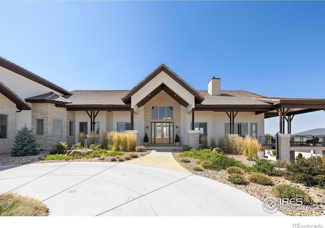 view of front of property with french doors, stucco siding, stone siding, and a chimney