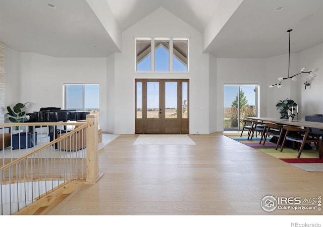 foyer featuring baseboards, high vaulted ceiling, and wood finished floors