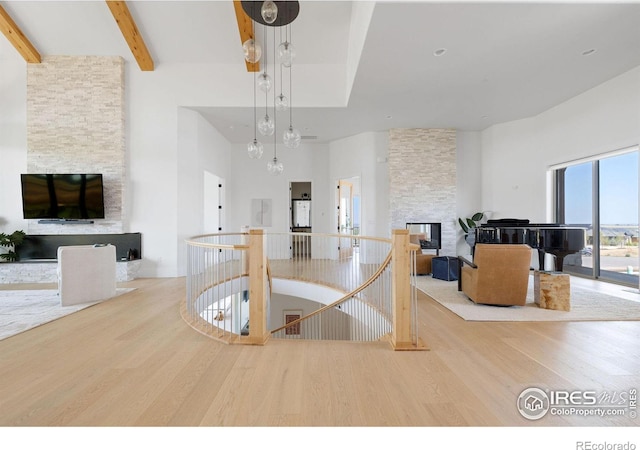 dining room with a fireplace, a towering ceiling, beam ceiling, and wood finished floors