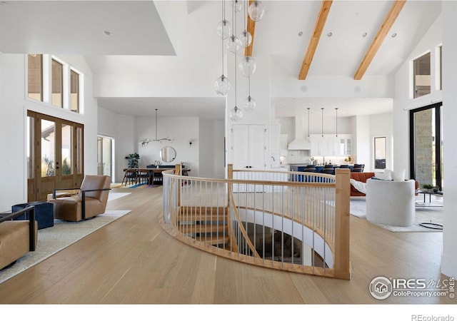 interior space with custom range hood, light wood-type flooring, open floor plan, beamed ceiling, and high vaulted ceiling