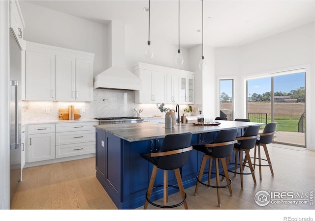 kitchen with custom exhaust hood, a kitchen bar, backsplash, and appliances with stainless steel finishes