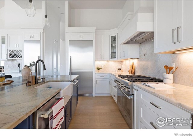 kitchen featuring custom exhaust hood, high quality appliances, and white cabinetry