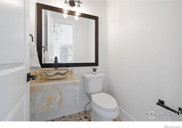 bathroom featuring toilet, vanity, and baseboards