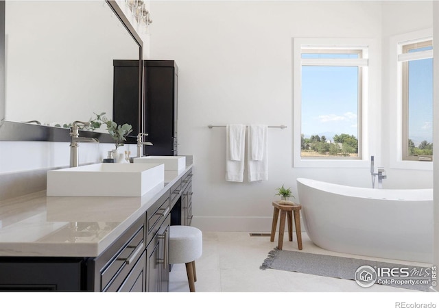 bathroom featuring a freestanding bath, double vanity, baseboards, and a sink