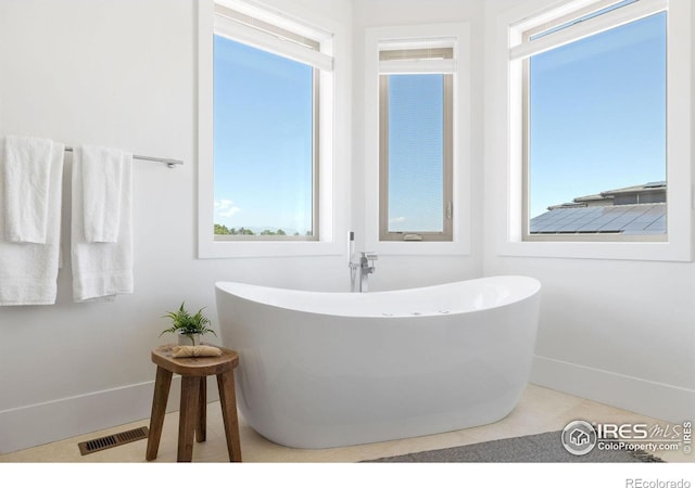 full bath with visible vents, baseboards, and a freestanding tub