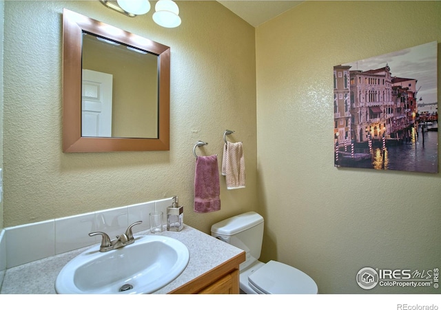835 Kane Dr Unit 25, Longmont, CO 80501 - half bathroom featuring toilet, vanity, and a textured wall