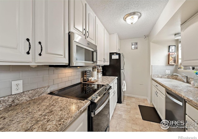 1616 Longbow Ct, Lafayette, CO 80026 - kitchen featuring appliances with stainless steel finishes, white cabinetry, backsplash, a textured ceiling, and light stone finish floors