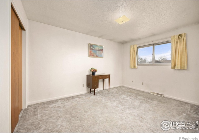 carpeted bedroom with visible vents, baseboards, and a textured ceiling