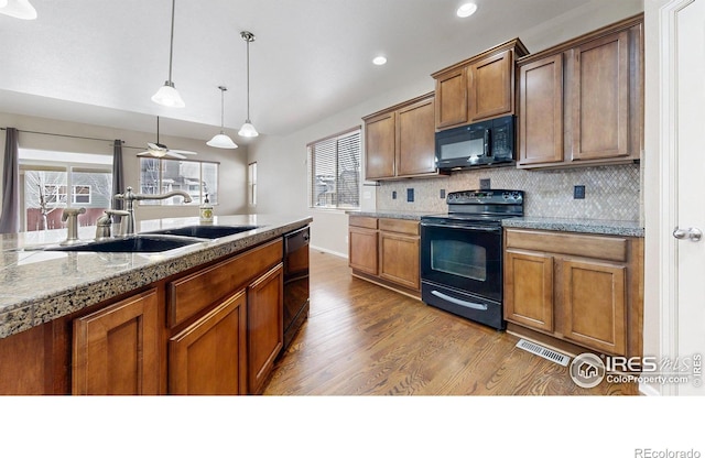 5543 Calgary St, Timnath, CO 80547 - kitchen with black appliances, a sink, dark wood-type flooring, backsplash, and pendant lighting