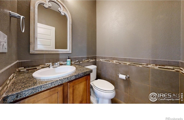 5543 Calgary St, Timnath, CO 80547 - half bathroom featuring vanity, toilet, tile walls, and a textured wall