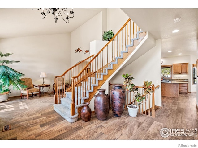 stairs with baseboards, recessed lighting, wood finished floors, and a notable chandelier