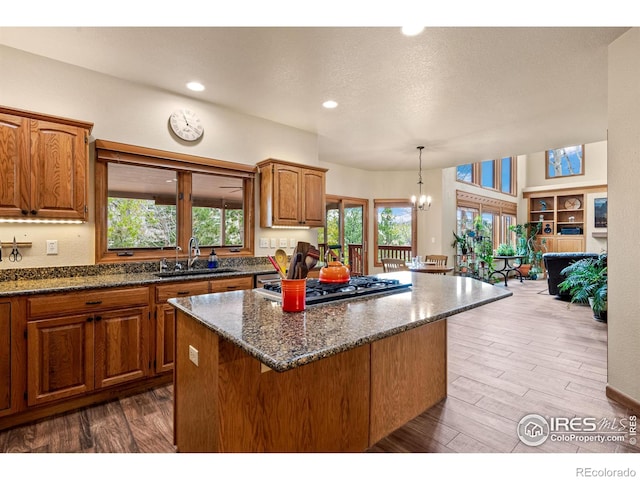 kitchen featuring a sink, a center island, stainless steel gas stovetop, and dark wood-type flooring