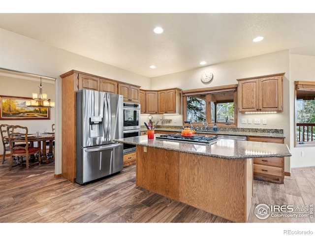 kitchen with dark stone counters, a kitchen island, stainless steel appliances, and light wood finished floors