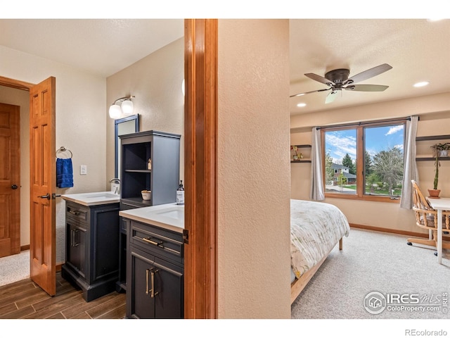 carpeted bedroom with wood finished floors, a sink, baseboards, a textured wall, and recessed lighting