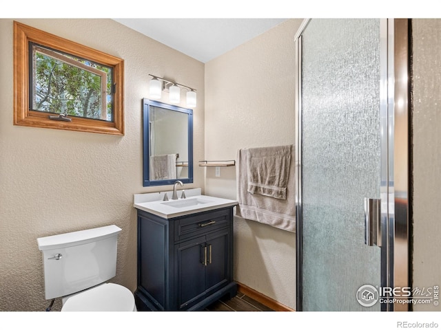 bathroom featuring vanity, a textured wall, toilet, and a shower stall